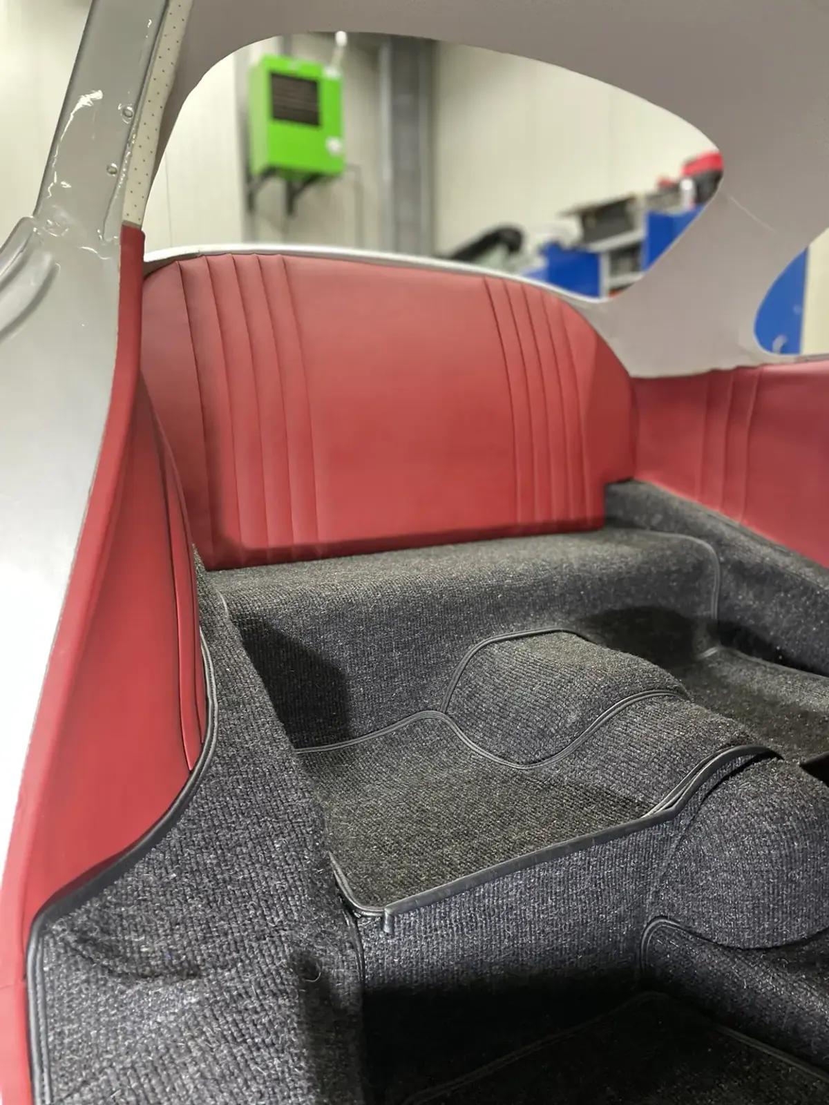 Klassischer Fahrzeuginnenraum mit roten Verkleidungen und grauem Teppich